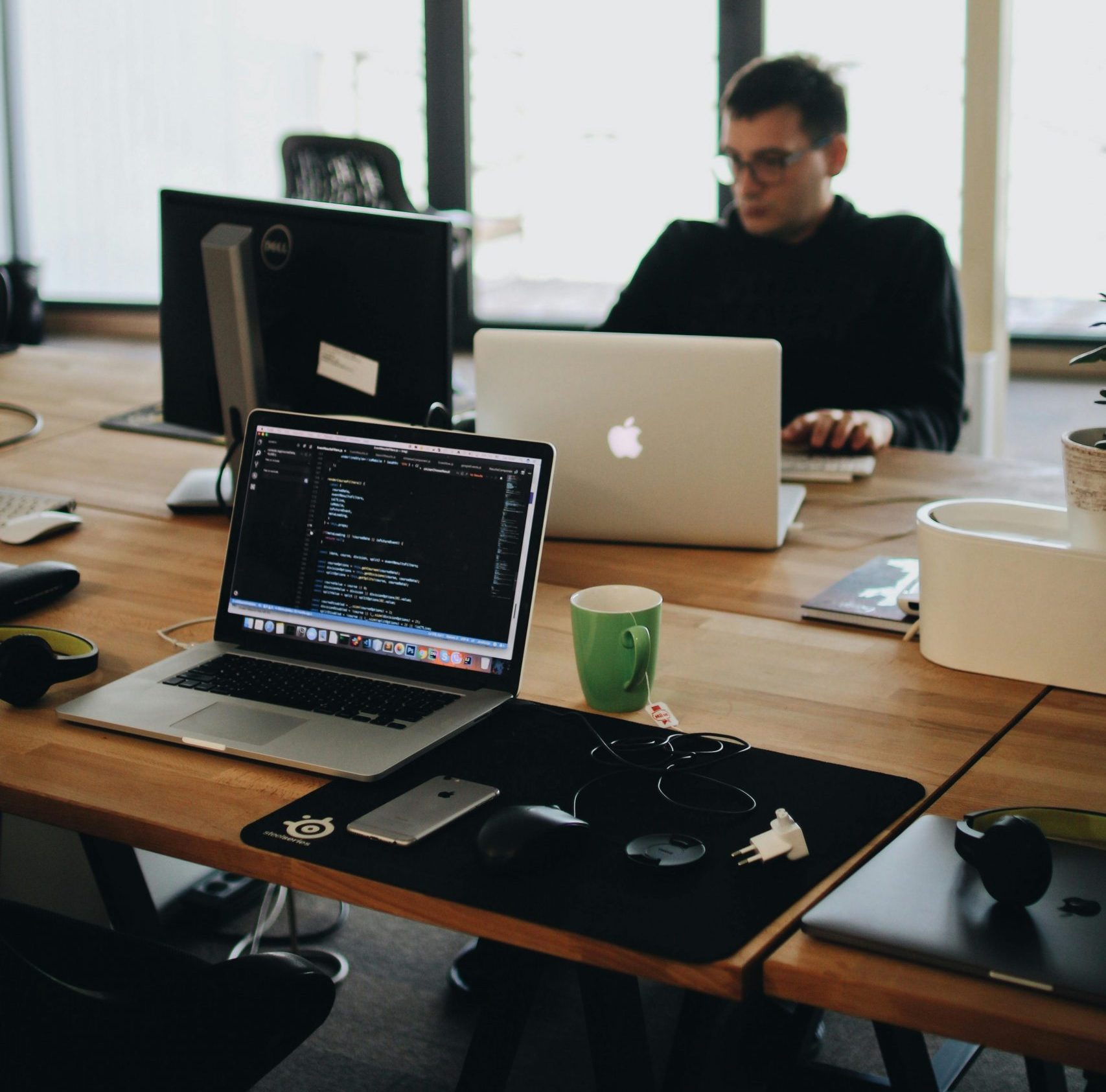 A web developer working on code in a modern office setting with multiple devices.